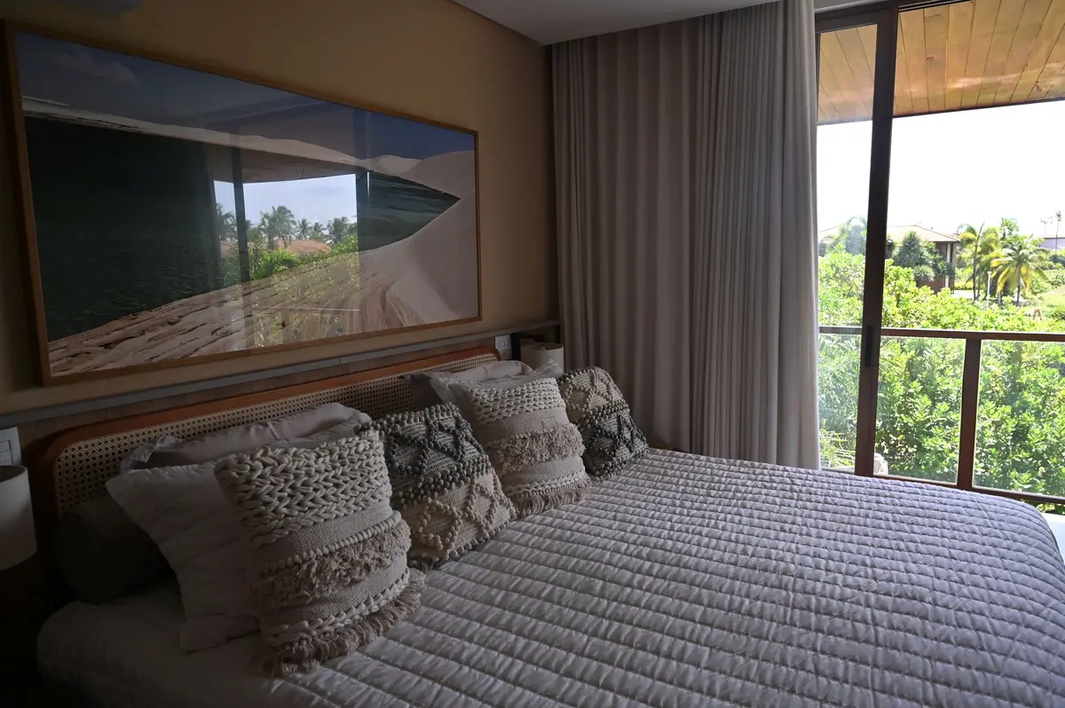 Cama de casal com porta de vidro para a varanda e vista para o verde